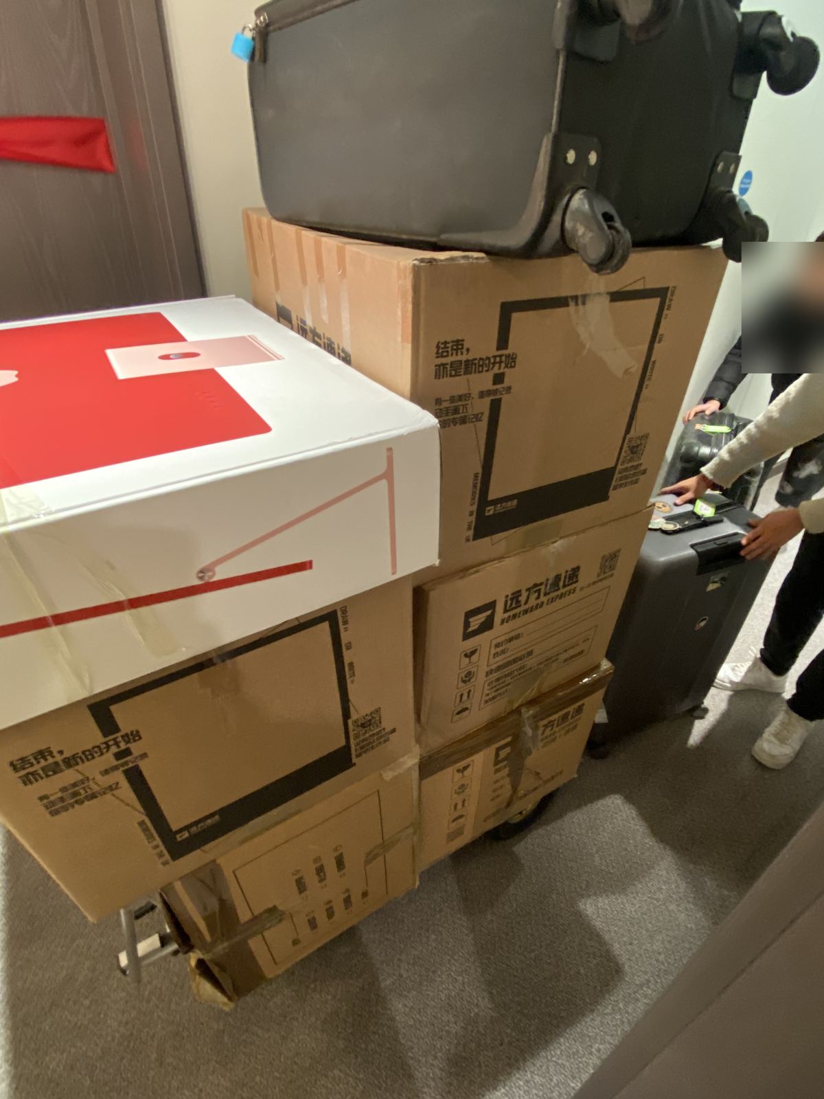 Boxes and a suitcase stacked on a hand truck at a customer's door, ready to be carried out.