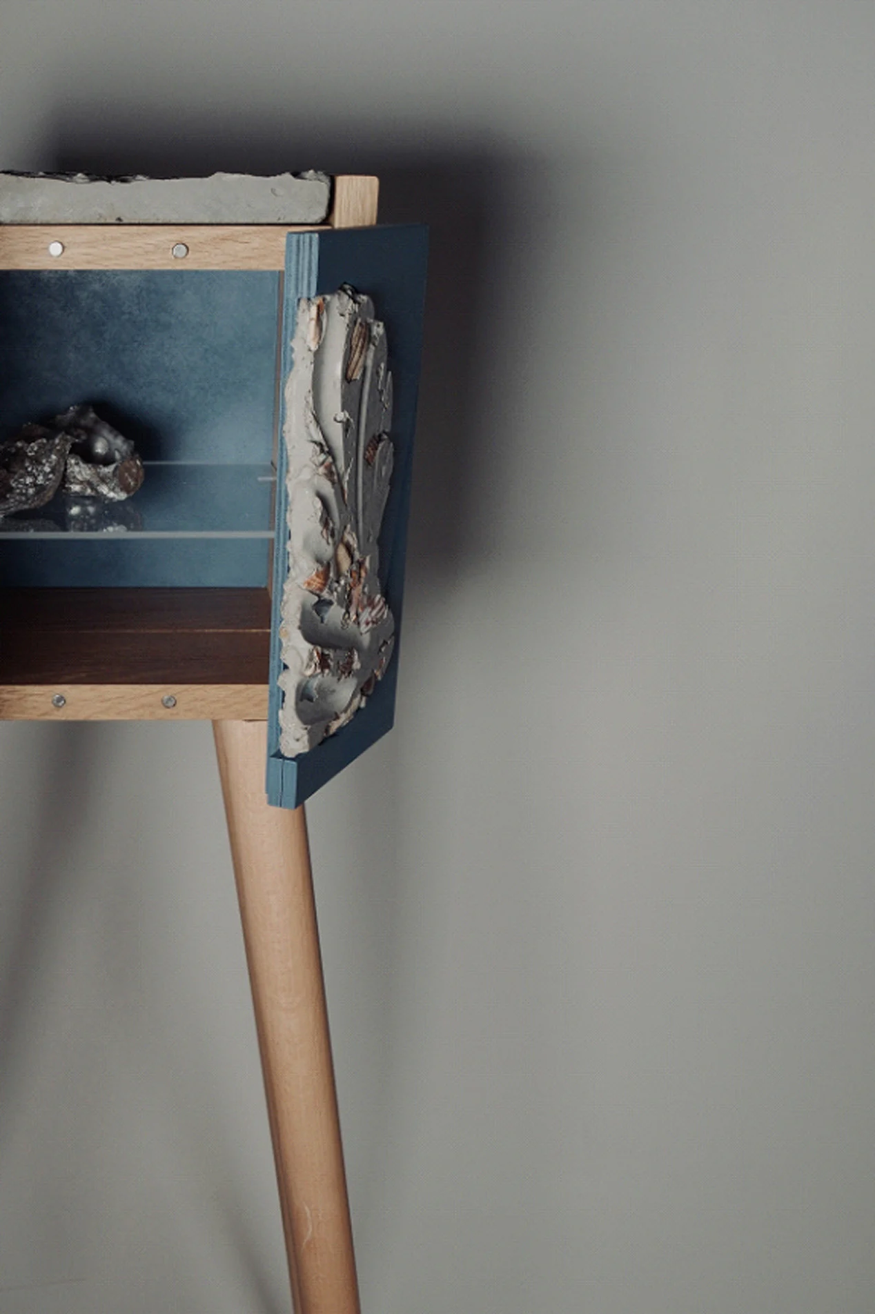 Side view of the open cabinet on its leg, with the glass shelf inside