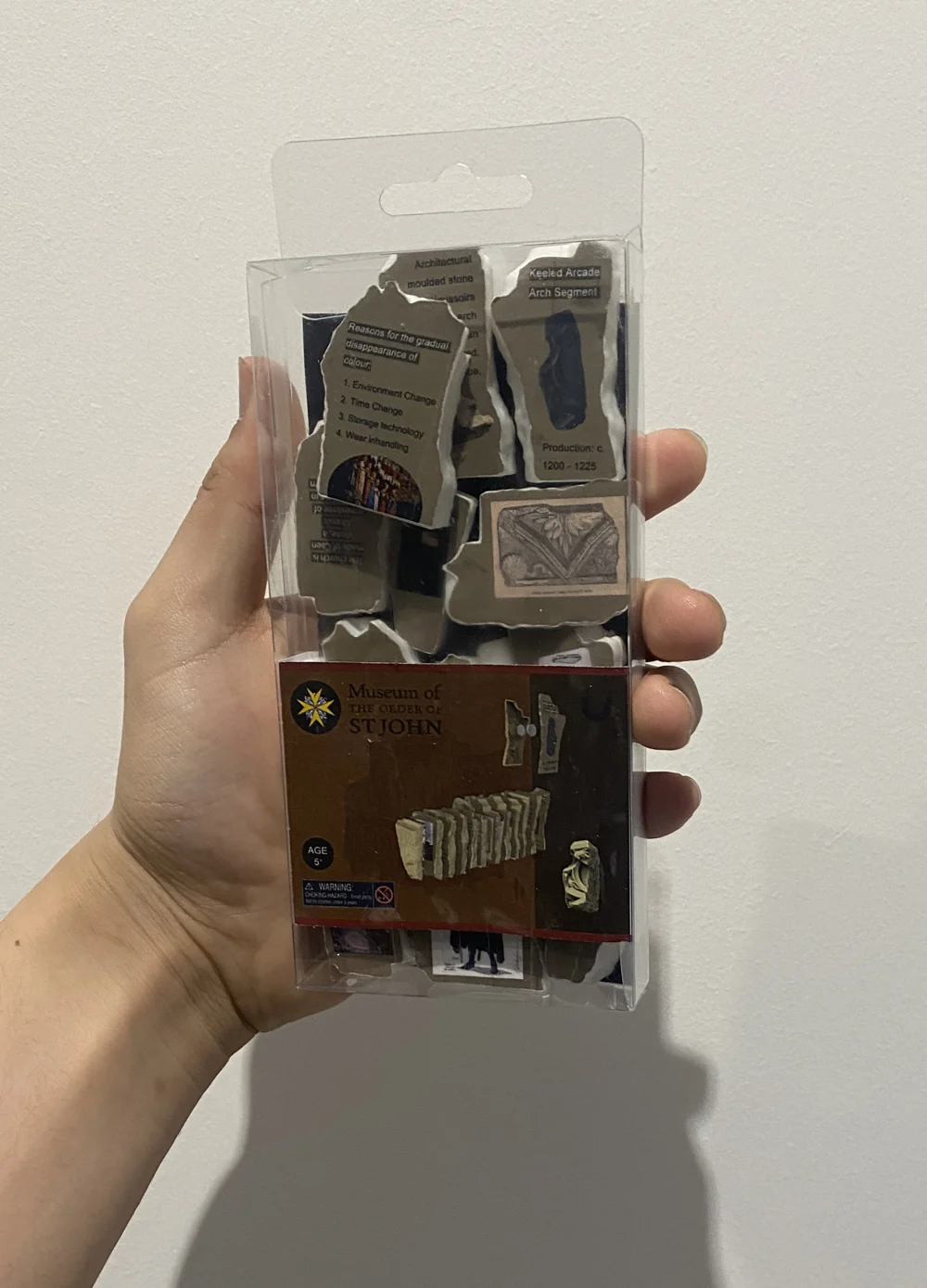The finished prototype pack held in a hand: printed slices behind a clear box with the museum cover