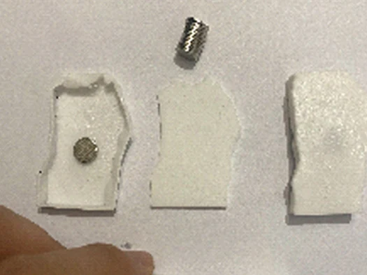 White 3D printed test slices, one with a magnet set into its face