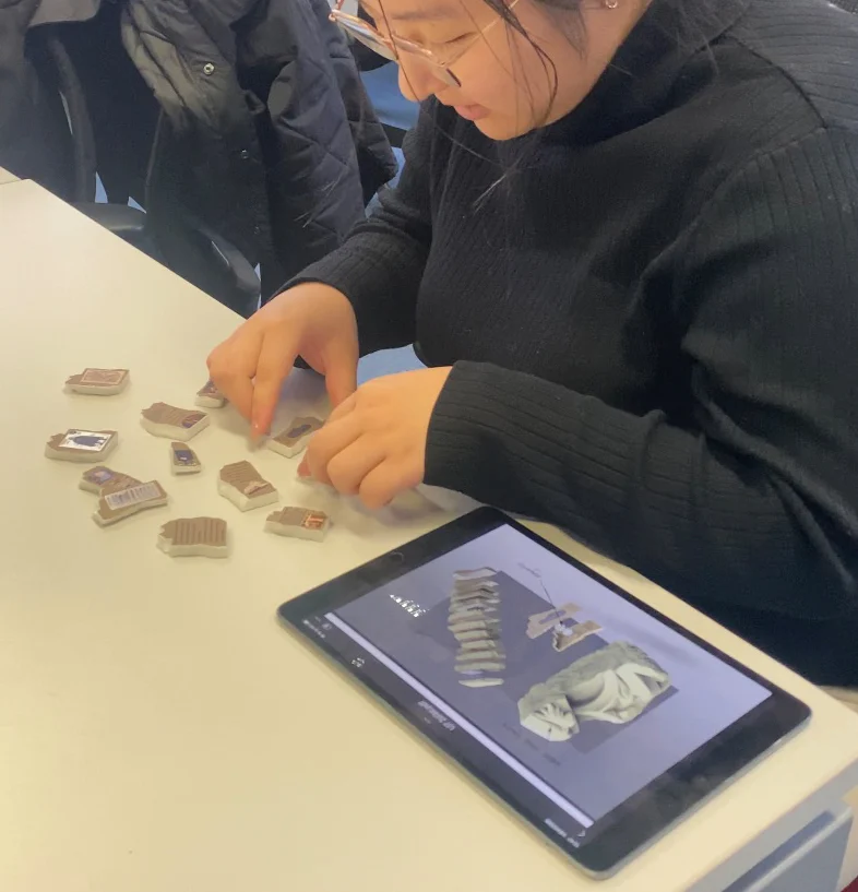 A student who had never seen the kit tries to assemble the slices, with the rendering on a tablet beside her